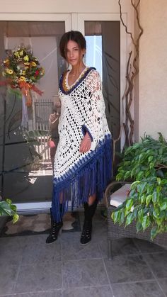 a woman standing in front of a door wearing a crocheted shawl and boots