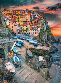 the boats are lined up on the dock by the water's edge in front of colorful buildings