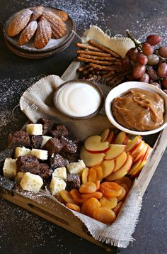 an assortment of fruit, crackers, and nuts on a tray with chocolate spread