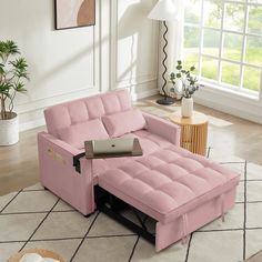 a living room with a pink couch and coffee table on the floor next to a potted plant