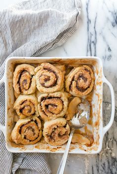 cinnamon rolls in a baking dish with a spoon