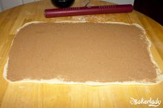 an uncooked dough on a wooden table with a red rolling pin next to it