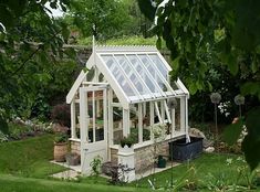 a small greenhouse in the middle of some grass