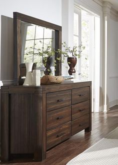 a dresser with a mirror and vases on it