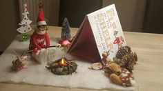 a table topped with figurines and a christmas card next to an elf's tent