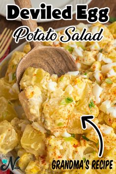 deviled egg potato salad in a white bowl with a wooden spoon on the side