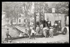 an old black and white photo of men working on a machine in the woods with other people around it