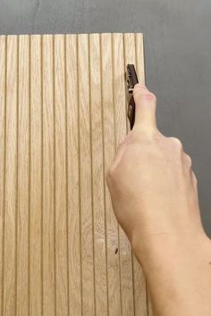 a person using a pair of scissors to cut wood strips on a piece of plywood