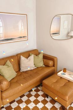 a brown leather couch sitting in a living room next to a coffee table and ottoman