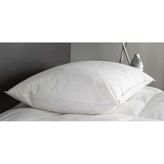 two white pillows sitting on top of a bed next to a night stand with an alarm clock