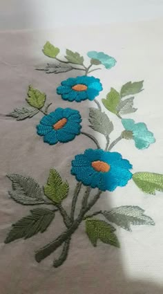 blue flowers are embroidered onto the side of a bed