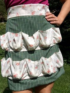 a woman wearing a skirt with ruffles on the front and bottom, standing in grass