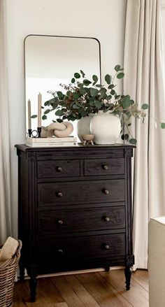 a dresser with a mirror and some plants on it