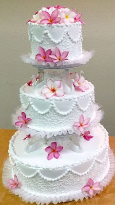 three tiered wedding cake with pink flowers on the top and white ruffles