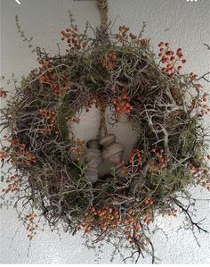 a wreath hanging from the side of a building with red berries on it and branches