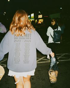 a woman is walking down the street with her back to the camera, carrying bags