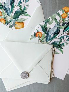 some white envelopes with oranges and leaves on them