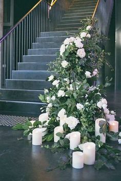 candles and flowers sit on the floor next to some stairs in front of a set of stairs