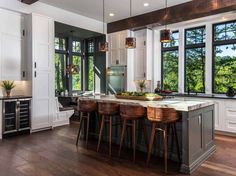 an image of a kitchen with stools in front of the counter top and windows