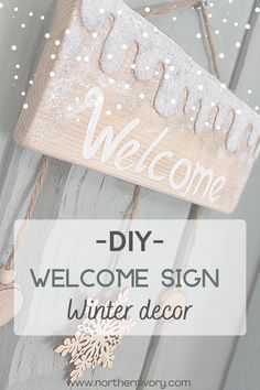 a welcome sign hanging from the side of a wooden door with snowflakes on it