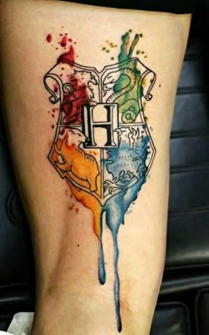 harry potter house tattoo on the side of a woman's leg with watercolor splashs