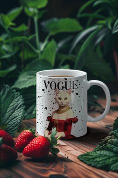 a coffee mug with a cat on it next to strawberries