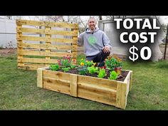 a man standing next to a wooden planter box filled with flowers and plants in it