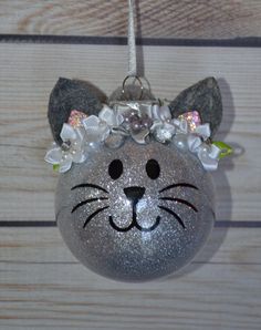 a silver ornament with a cat face on it's head and flowers in its hair