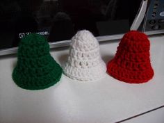 three crocheted christmas hats sitting on top of a counter next to a microwave