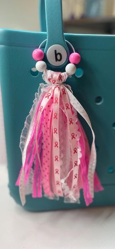 a blue purse with pink and white decorations hanging from it's side on a table