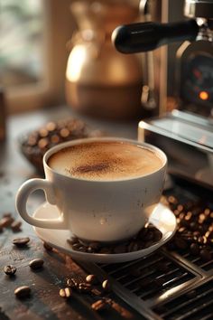 a cup of coffee sitting on top of a saucer next to some beans and an espresso machine