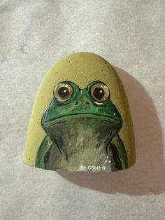 a painted frog sitting on top of a rock