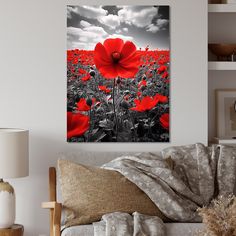 a red flower is in the middle of a black and white field with clouds above it