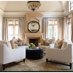 a living room filled with furniture and a clock on the wall above it's fireplace