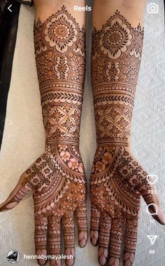 two hands with henna tattoos on them, one is showing the intricate pattern and the other