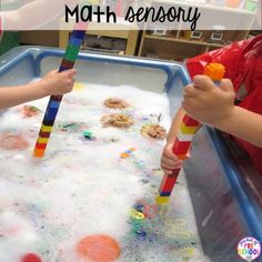 two children are playing with toys in a play table filled with foam and sand that says, clean toys in the sensory table