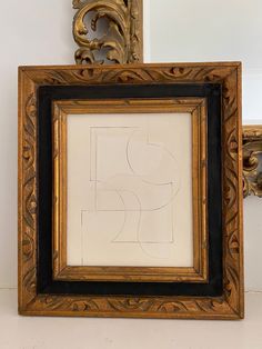 an ornate gold frame with a black border around it and a drawing in the middle