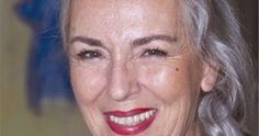 an older woman with gray hair smiling at the camera and wearing a black shirt, red lipstick