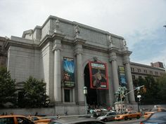 cars are parked in front of an old building with movie posters on the wall and windows