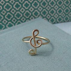 a gold ring with a musical note on it's middle finger, sitting on top of a blue fabric