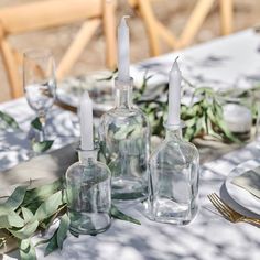 the table is set with clear bottles and candles