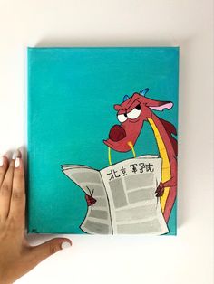 a hand is holding up a book with an image of a dragon reading a newspaper