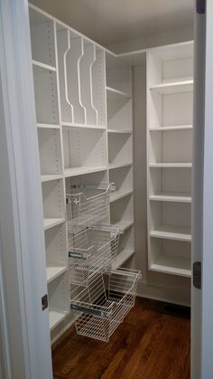 an empty closet with white shelving and baskets on the bottom shelf in front of it