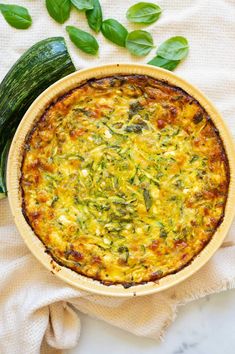 a quiche with spinach and cheese in a wooden bowl on a white cloth