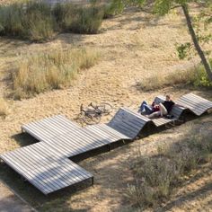 a man laying on top of a wooden platform in the middle of a dry grass field