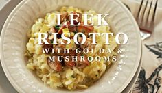 a white bowl filled with pasta and mushrooms on top of a table next to a fork