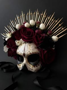 a skull with flowers and spikes on it's head sits next to a black ribbon