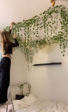 a woman is hanging plants on the wall