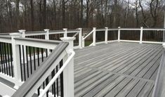 a wooden deck with white railings next to trees