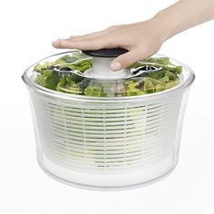 a person using a food chopper on top of lettuce in a pot with the lid open